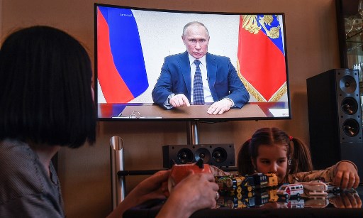 A woman watches a live broadcast of Russian President Vladimir Putin's address to the nation over the coronavirus outbreak, in her appartment in Moscow on April 2, 2020. - President Vladimir Putin on April 2, 2020 aid Russians will continue not going to work while receiving pay until the end of the month to contain the spread of the Covid-19 pandemic caused by the novel coronavirus. (Photo by Alexander NEMENOV / AFP)