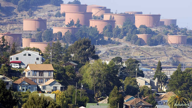 Homes sit below Chevron storage tanks on a hillside in Richmond, California, November 6, 2007. Oil prices slipped into negative territory on Wednesday, retreating from an all-time high above $98 a barrel as speculators took profits from the record rally. Picture taken November 6, 2007. REUTERS/Kimberly White (UNITED STATES)