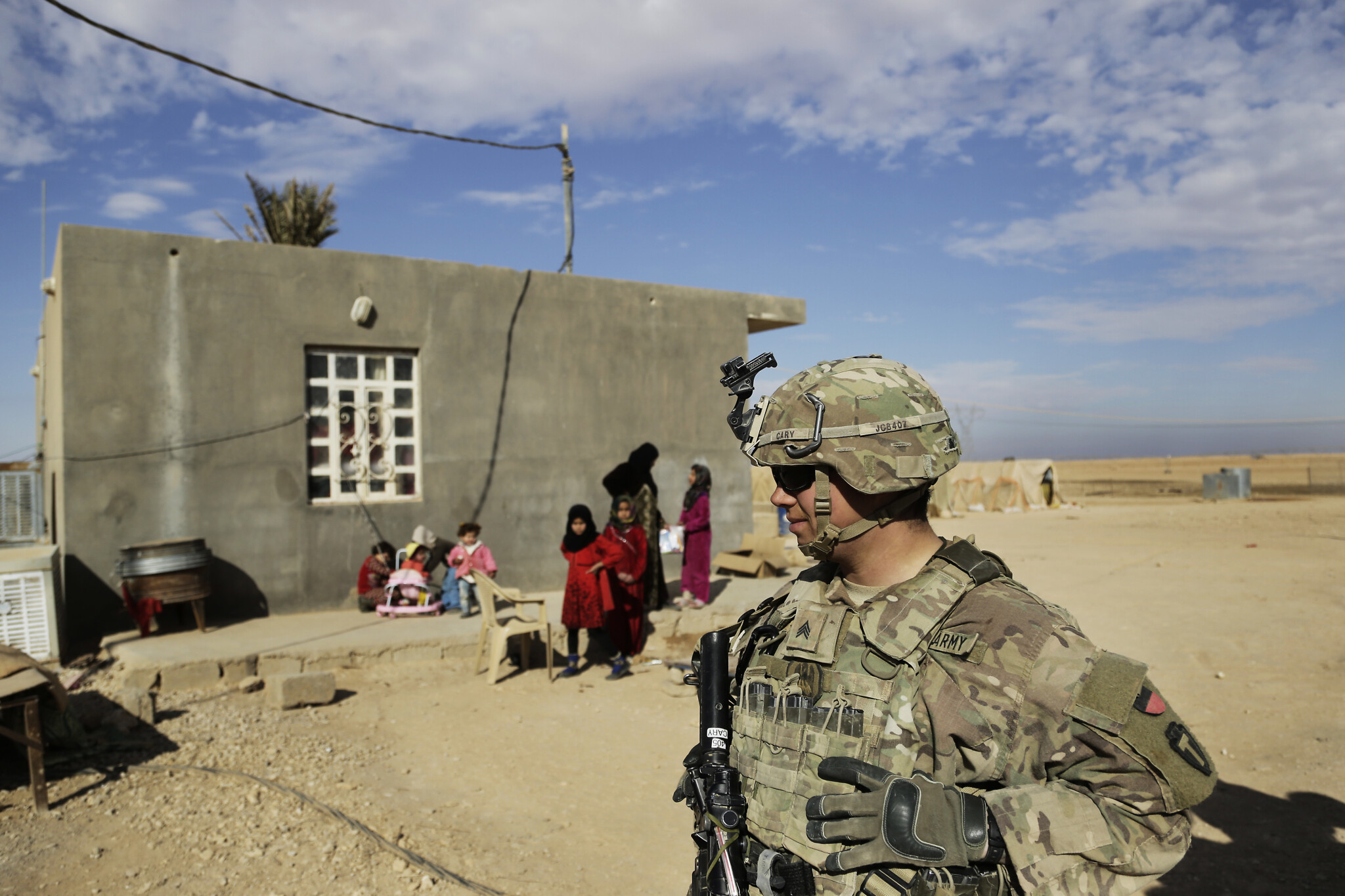 FILE - In this Jan. 27, 2018, file photo, U.S. Army soldiers speak to families in rural Anbar on a reconnaissance patrol near a coalition outpost in western Iraq. Iraq’s president has slammed comments by U.S. President Donald Trump who he says he wants to keep U.S. troops in Iraq “to watch Iran.” Barham Salih said Monday, Feb. 4, 2019 that Trump did not ask Iraq’s permission for American troops stationed there to watch Iran, describing his comments as “strange.”(AP Photo/Susannah George, File)