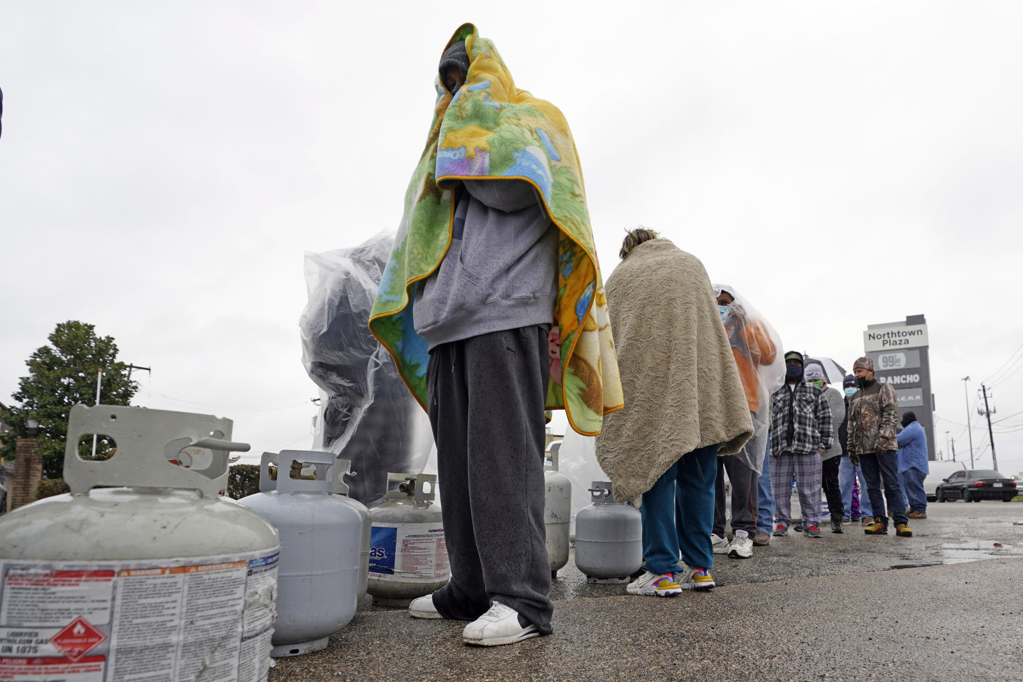 Carlos Mandez waits in line to fill his propane tanks Wednesday, Feb. 17, 2021, in Houston. Customers had to wait over an hour in the freezing rain to fill their tanks. Millions in Texas still had no power after a historic snowfall and single-digit temperatures created a surge of demand for electricity to warm up homes unaccustomed to such extreme lows, buckling the state's power grid and causing widespread blackouts. (AP Photo/David J. Phillip)