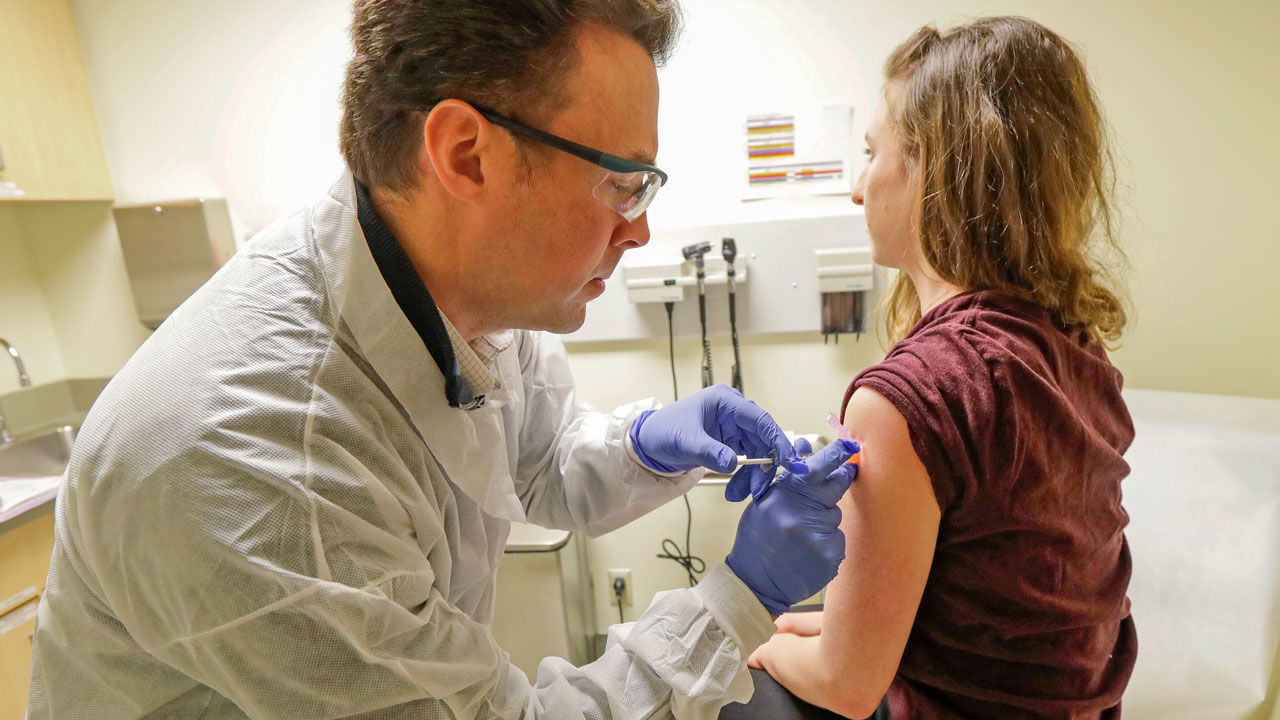 In this March 16, 2020, file photo, pharmacist Michael Witte, left, gives Rebecca Sirull a shot in the first-stage safety study clinical trial of a potential vaccine for COVID-19, the disease caused by the new coronavirus, Monday, March 16, 2020, at the Kaiser Permanente Washington Health Research Institute in Seattle. Sirull is the third patient to receive the shot in the study. Researchers say the first phase of human clinical trials for a COVID-19 vaccine in healthy volunteers in the Pittsburgh area could start in the coming months. (AP Photo/Ted S. Warren, File)