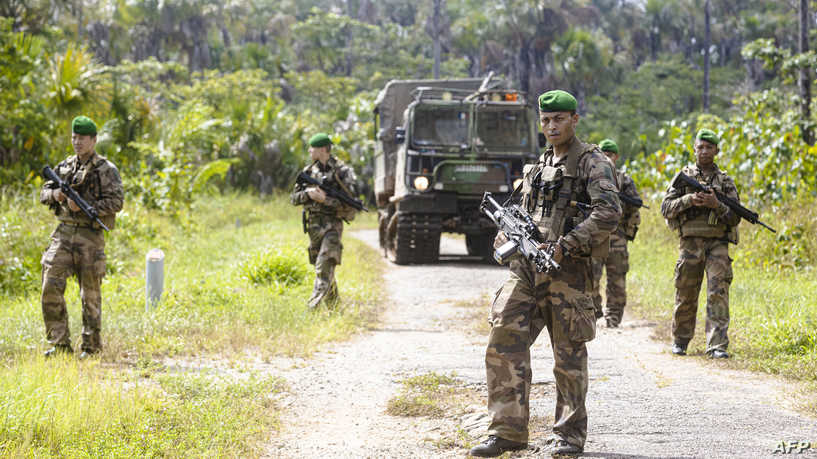 Soldiers of the French 3rd Foreign Infantry Regiment and a cynophilist with his dog, patrol next to a BV206 Tracked articulated vehicle as they take part in the training for the mission "Titan", which aims to protect the facilities of the launch sites of the Ariane, Soyuz and Vega rockets, at the Guiana Space Centre, in Kourou, in French Guiana, on October 22, 2021. (Photo by Jody AMIET / AFP)