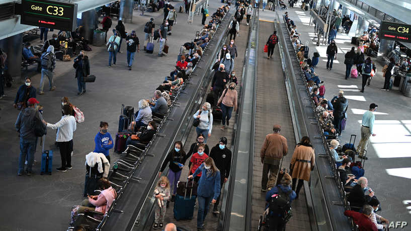 Travelers wear protective face masks at Denver International Airport on November 30, 2021 in Denver, Colorado as concern grows worldwide over the Omicron coronavirus variant. (Photo by Robyn Beck / AFP)