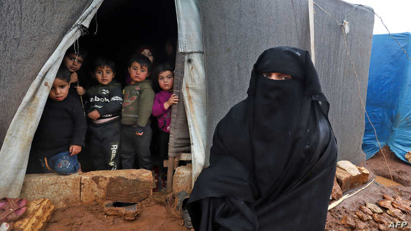 A woman and children pose for a picture at a camp for Syrians displaced by conflict that was flooded during heavy rains near the village of Kafr Uruq, in Syria's northern rebel-held Idlib province on December 8, 2021. (Photo by Abdulaziz KETAZ / AFP)