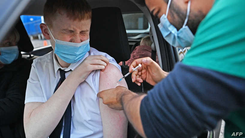 A boy receives a Covid-19 vaccine at a drive-through NHS (National Health Service) vaccination centre outside Ewood Park, Blackburn Rovers Football Club in Blackburn in north-west England on January 17, 2022, as the Omicron coronavirus variant spreads in the country. (Photo by Paul ELLIS / AFP)