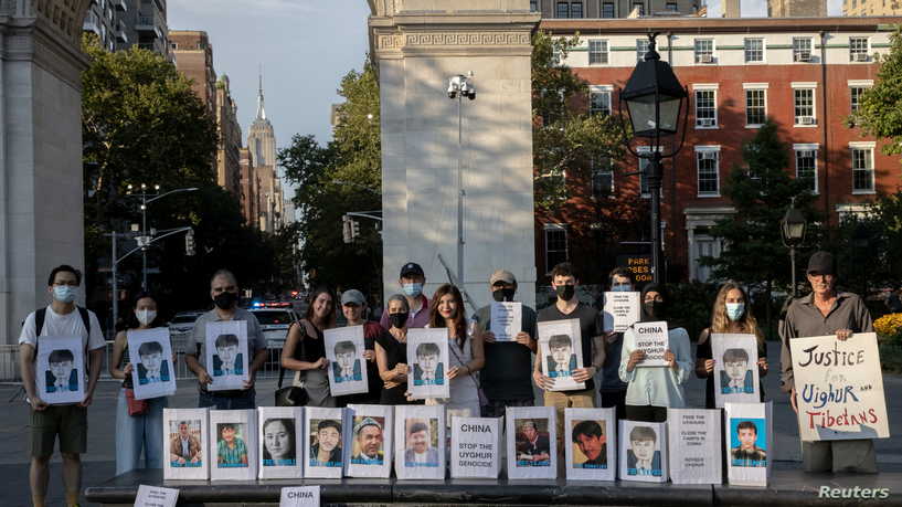 Protesters hold photos of Ekpar Asat, who is believed to be held in solitary confinement since 2019 according to media reports, during a rally in support of the Uyghurs, in New York City, New York, U.S. August 12, 2021. REUTERS/Jeenah Moon