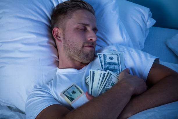 Man Sleeping On Bed With Bundle Of Currency Notes