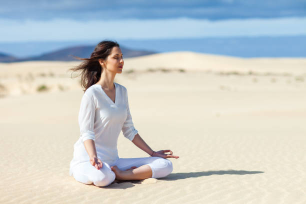 Young woman meditating in Lotus Pose in desert on Canary Islands, Spain. Padmasana. Relax concept