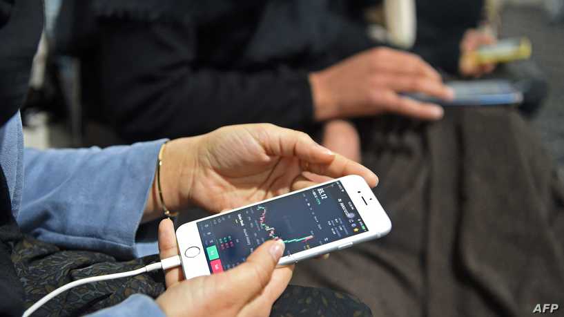 In this photo taken on February 15, 2022, university students use cryptocurrency on their smartphones after an interview with AFP, at a exchange currency market in Herat. - Since the Taliban returned in August 2021, Afghanistan's economy has virtually collapsed and the country is in the grip of a crisis caused by the seizure of billions of dollars of assets held abroad. But digital currencies and their decentralised architecture, impervious to international sanctions, are allowing a handful of young Afghans to avoid the worst of the crisis. (Photo by Wakil KOHSAR / AFP) / TO GO WITH: Afghanistan-economy-crypto, FOCUS by Romain FONSEGRIVES with Qubad WALI