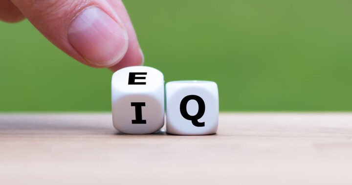 Hand turns a dice and changes the expression "IQ" (Intelligence Quotient) to "EQ" (Emotional Intelligence/Quotient).